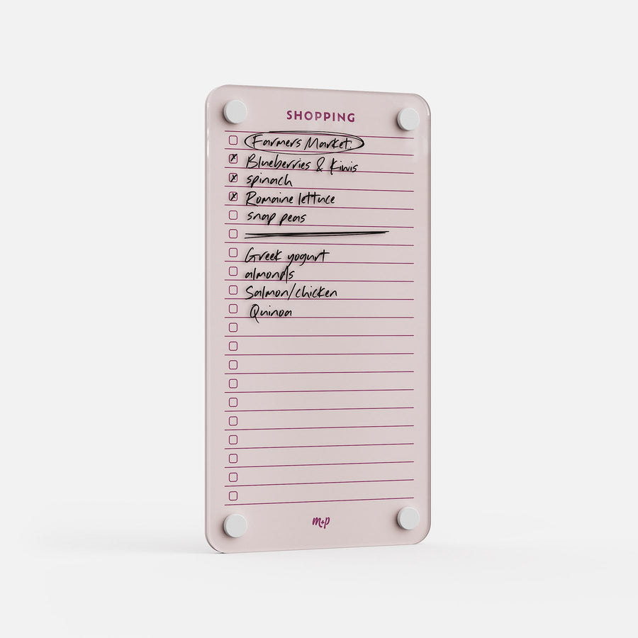 Shopping List 59 is a pink reusable kitchen list featuring checked and crossed-off grocery items—blueberries, spinach, romaine lettuce, snap peas, Greek yogurt, almonds, salmon/chicken, and quinoa. Four magnets hold it in place for easy meal planning.