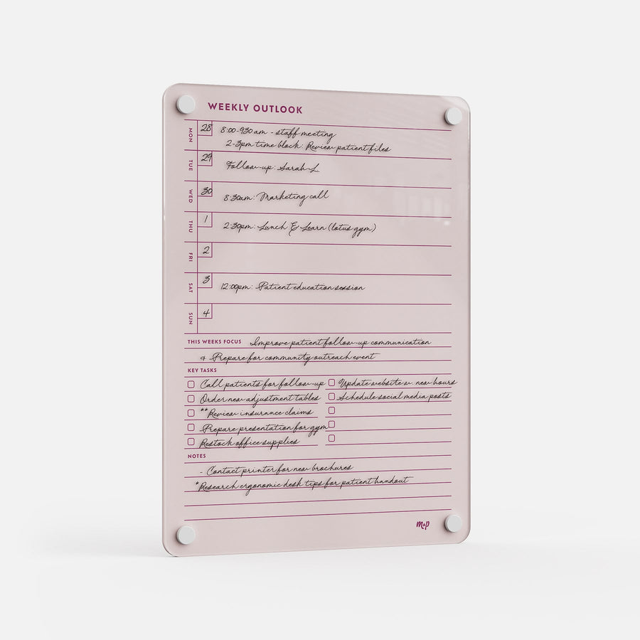 The Weekly Outlook 811 is a pink weekly planner board with handwritten notes, schedules, checkboxes for tasks, space for weekly focus and key ideas. It mounts easily using four white corner magnets.