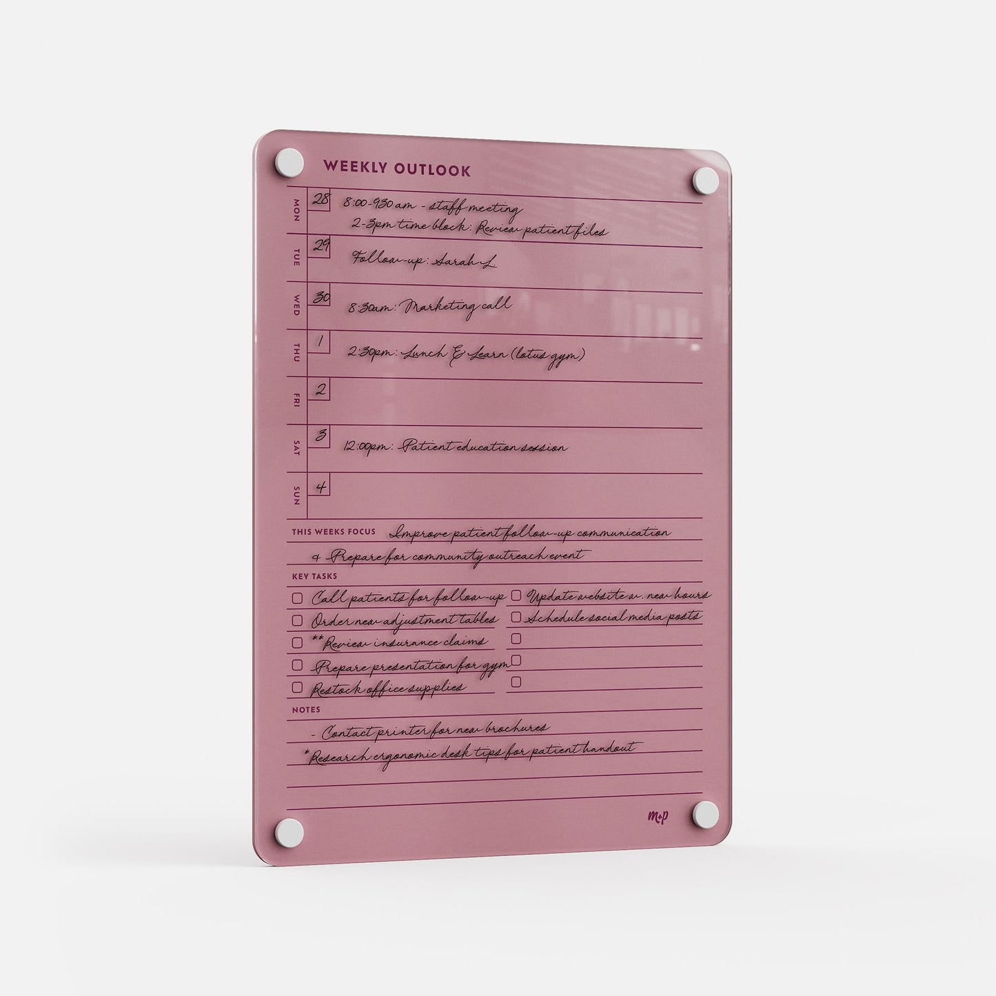 The Weekly Outlook 811 is a pink acrylic weekly planner board with handwritten schedules, black marker notes, sections for daily appointments, weekly focus, key tasks, and notes—a stylish organizer mounted via four corner holes.