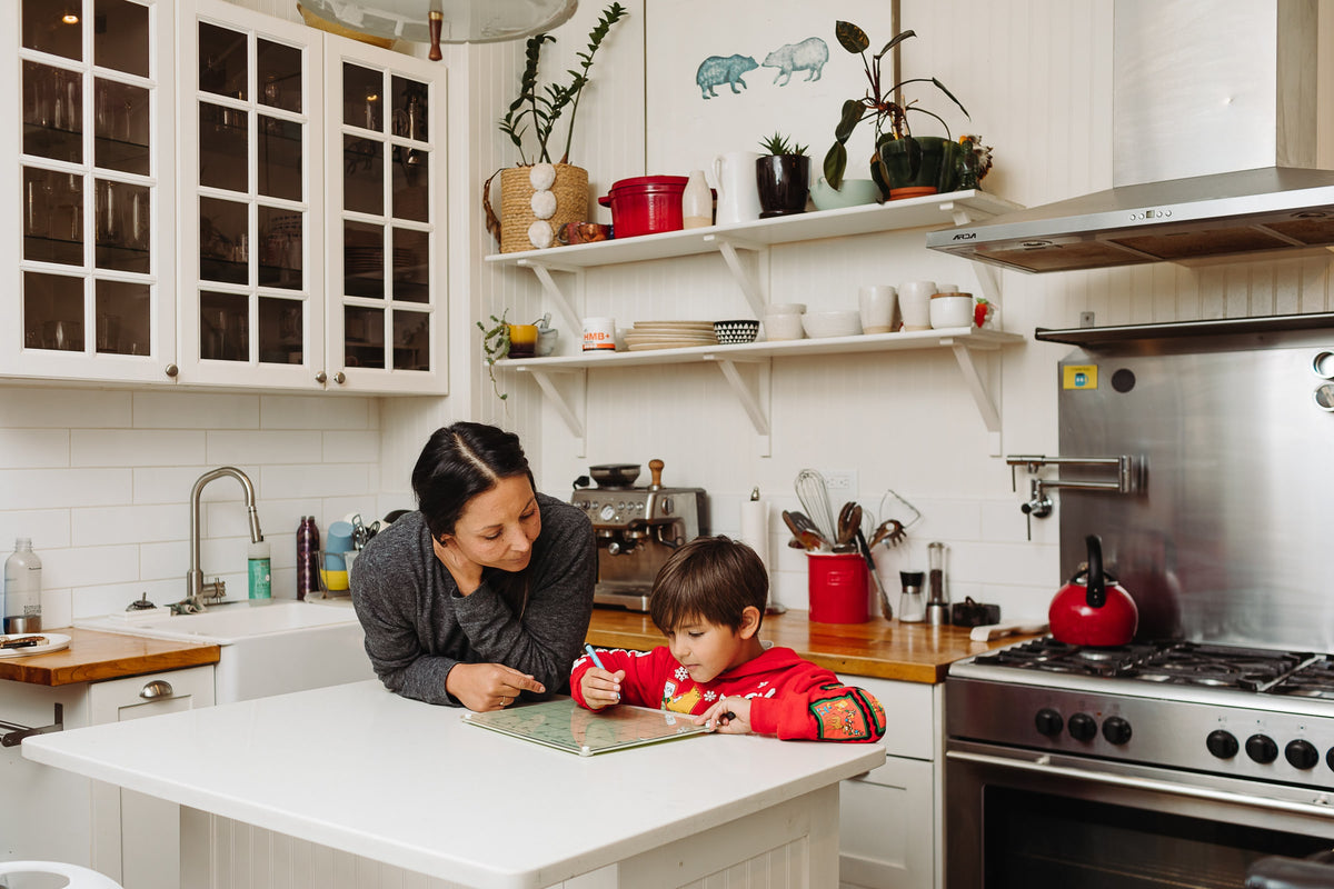 Mother and young son filling in a Matcha green magnetic dry erase monthly calendar at a kitchen island