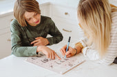 Mother and son using a Monkey and Pebbles magnetic monthly calendar to plan their schedule together at a modern kitchen counter