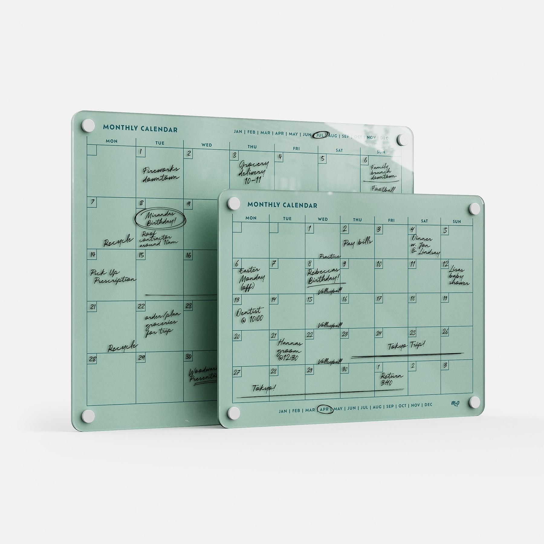 Two seafoam green Monthly Calendar 118 boards with handwritten black marker notes, displaying days of the week, months on the edge, and round corner magnets for mounting. The compact planners are angled and overlap each other.