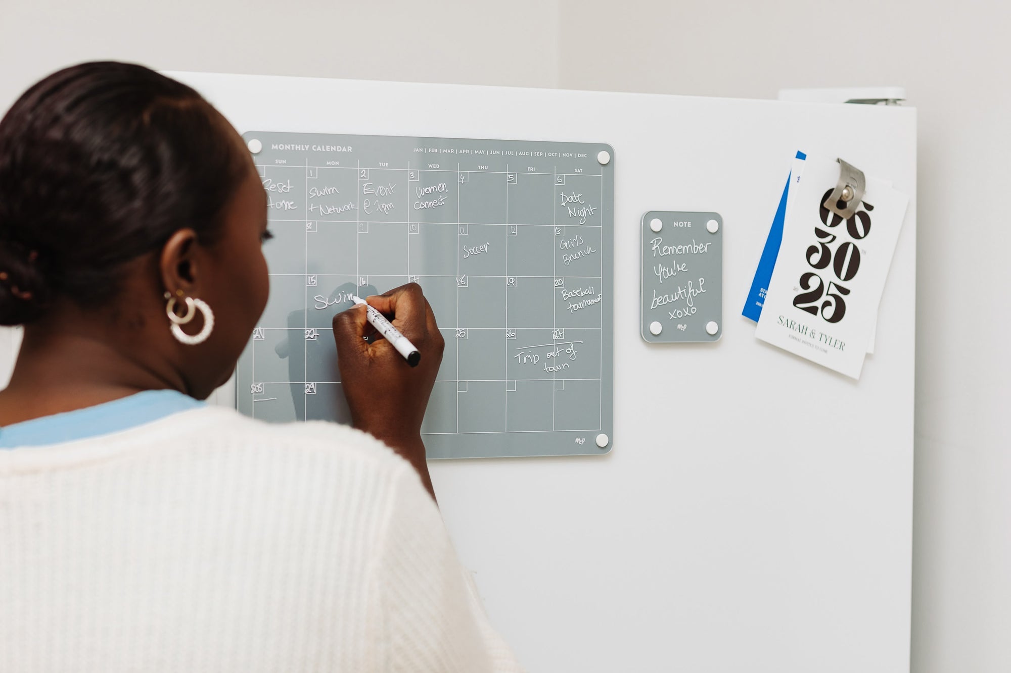 Slate grey magnetic dry erase monthly calendar and note board mounted side by side on a white wall