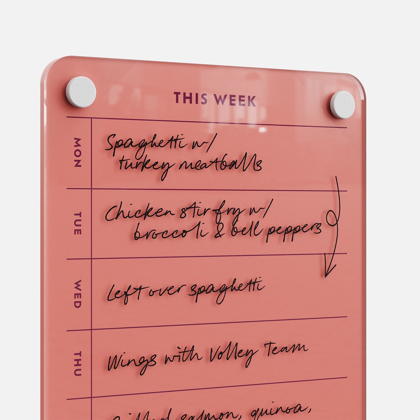 The This Week 69 pink dry-erase meal planner on the wall displays handwritten plans—spaghetti, chicken stir fry, leftover spaghetti, and wings with the volleyball team—organizing your meals from Monday to Thursday.
