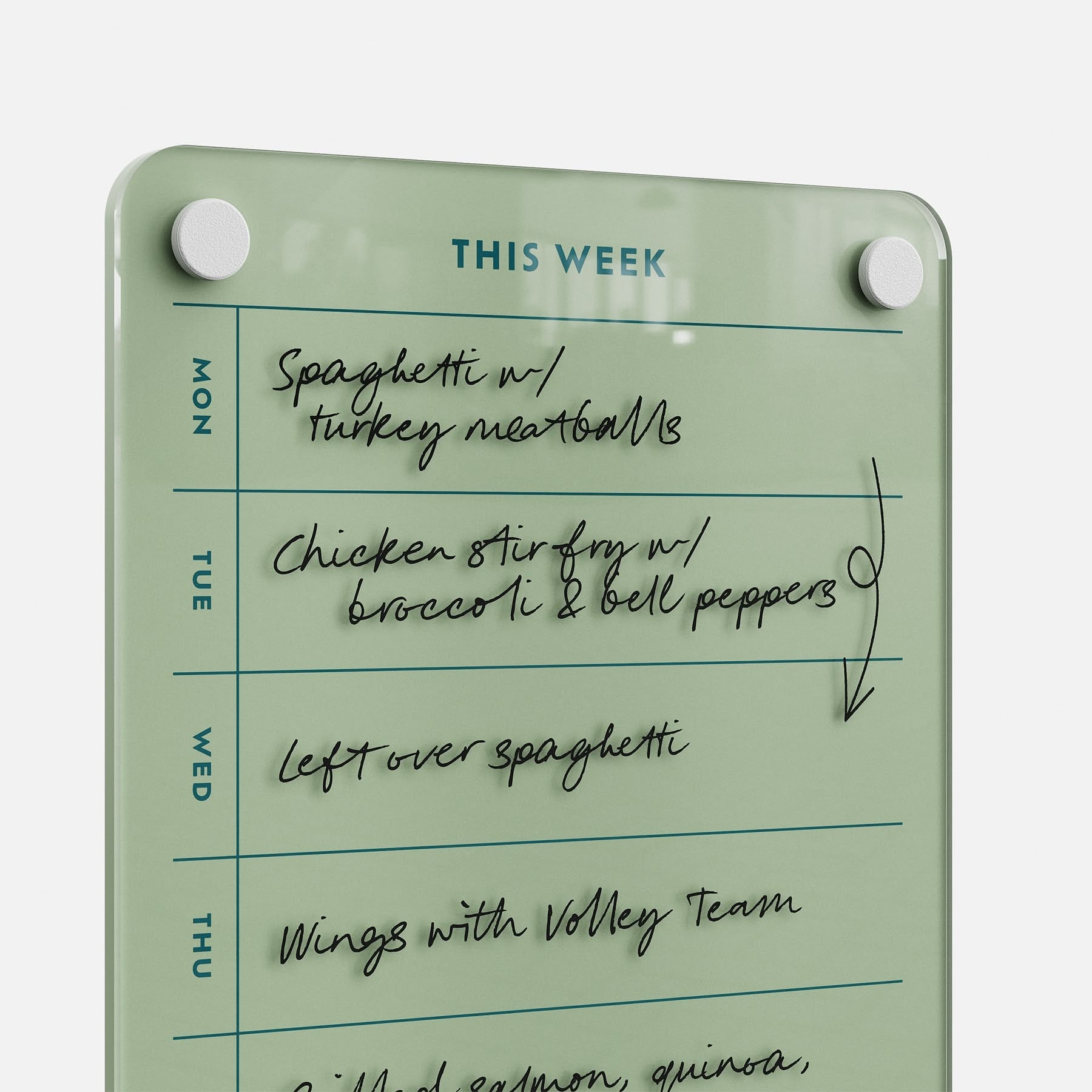 The This Week 69 glass dry-erase meal planner shows handwritten meals: Mon—spaghetti with turkey meatballs; Tue—chicken stir fry; Wed—leftover spaghetti; Thu—wings with the volleyball team.