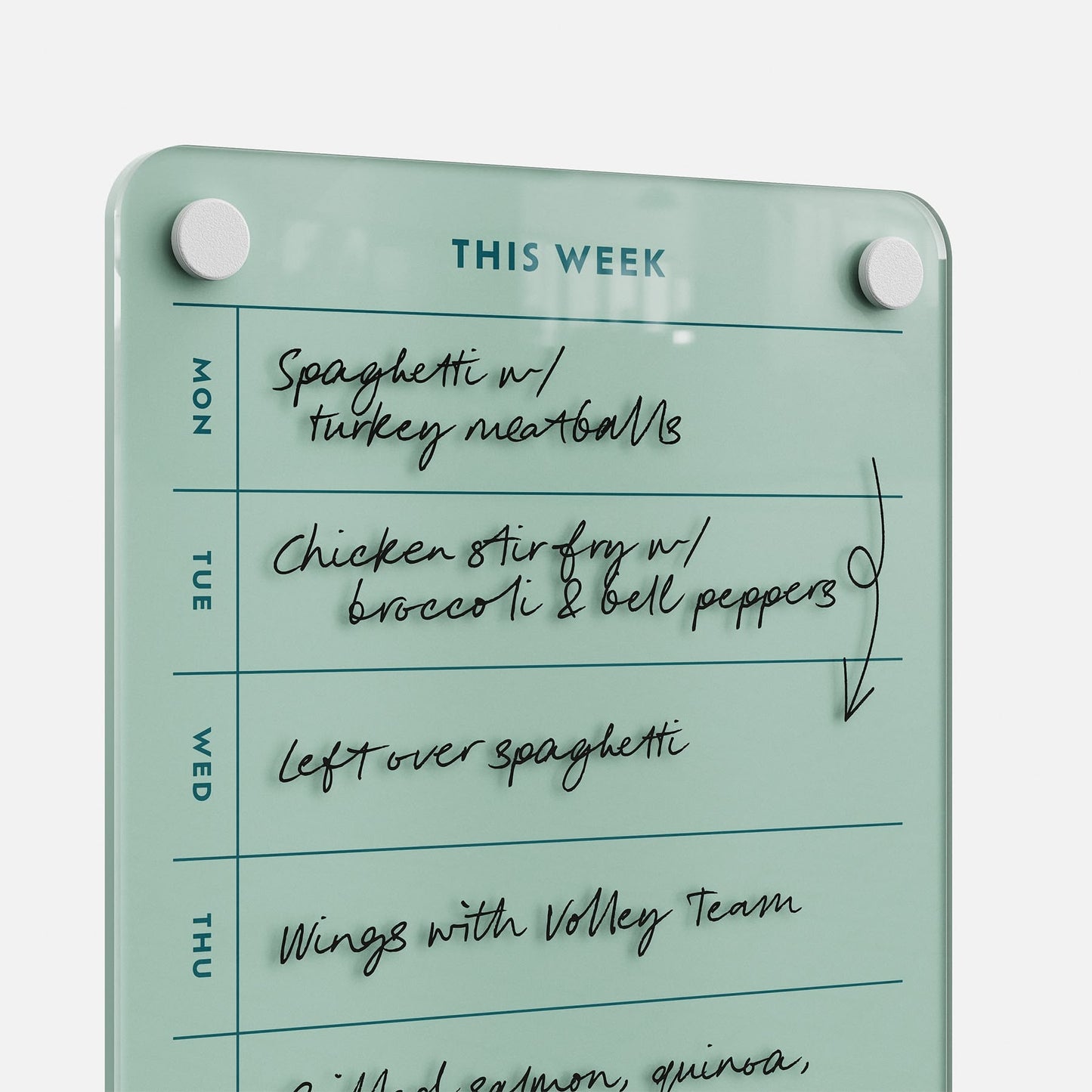 The This Week 69 glass meal planner board lists meals from Monday to Thursday: spaghetti, chicken stir fry with broccoli and bell peppers, leftover spaghetti, and wings with the volleyball team—a stylish kitchen organizer.