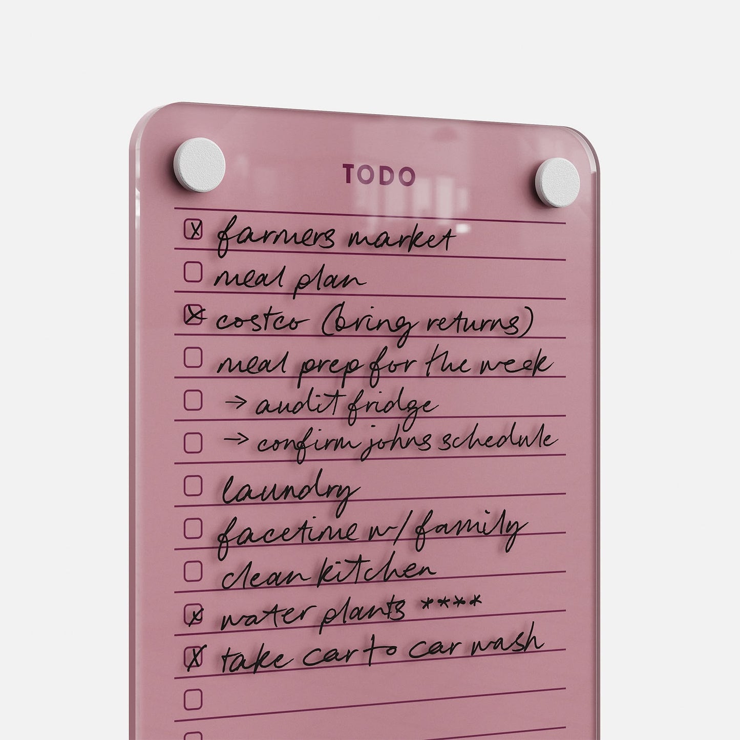The Todo List 59, a pink glass to-do board, displays completed tasks in black marker like farmers market and laundry. Two white magnets at the top showcase its efficiency as a daily organizer.