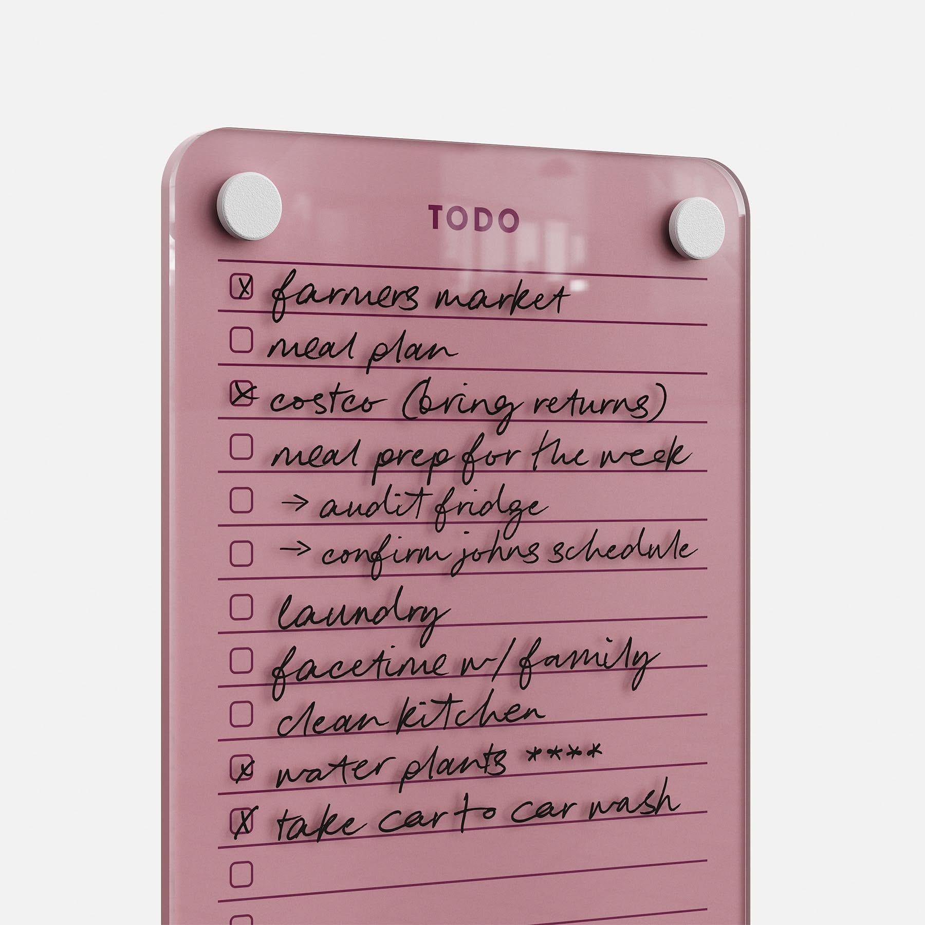 The Todo List 59, a pink glass to-do board, displays completed tasks in black marker like farmers market and laundry. Two white magnets at the top showcase its efficiency as a daily organizer.