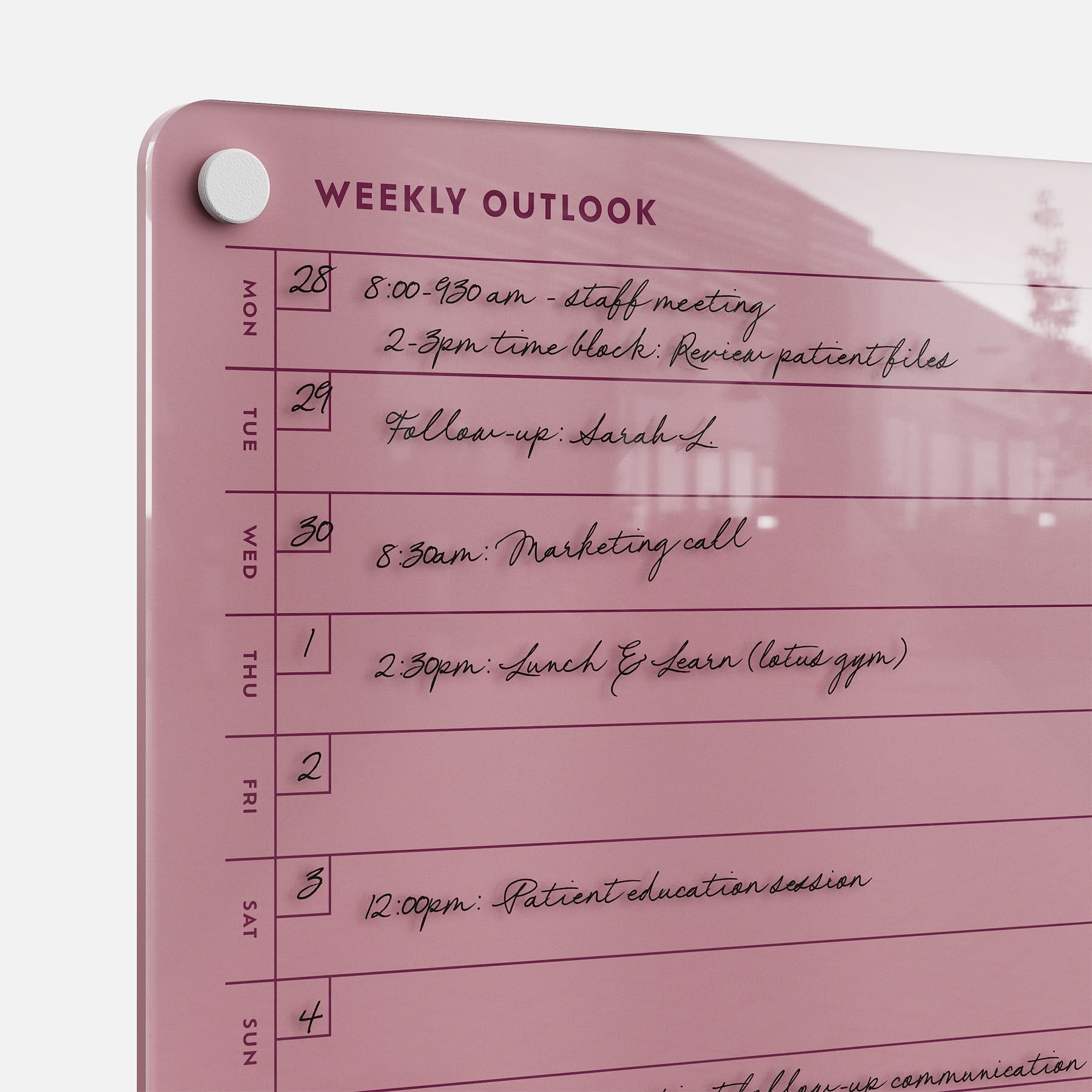 The Weekly Outlook 811, a pink dry-erase wall planner, organizes tasks and appointments such as meetings, Lunch & Learn, and patient education sessions, with days of the week listed on the left for easy weekly planning.
