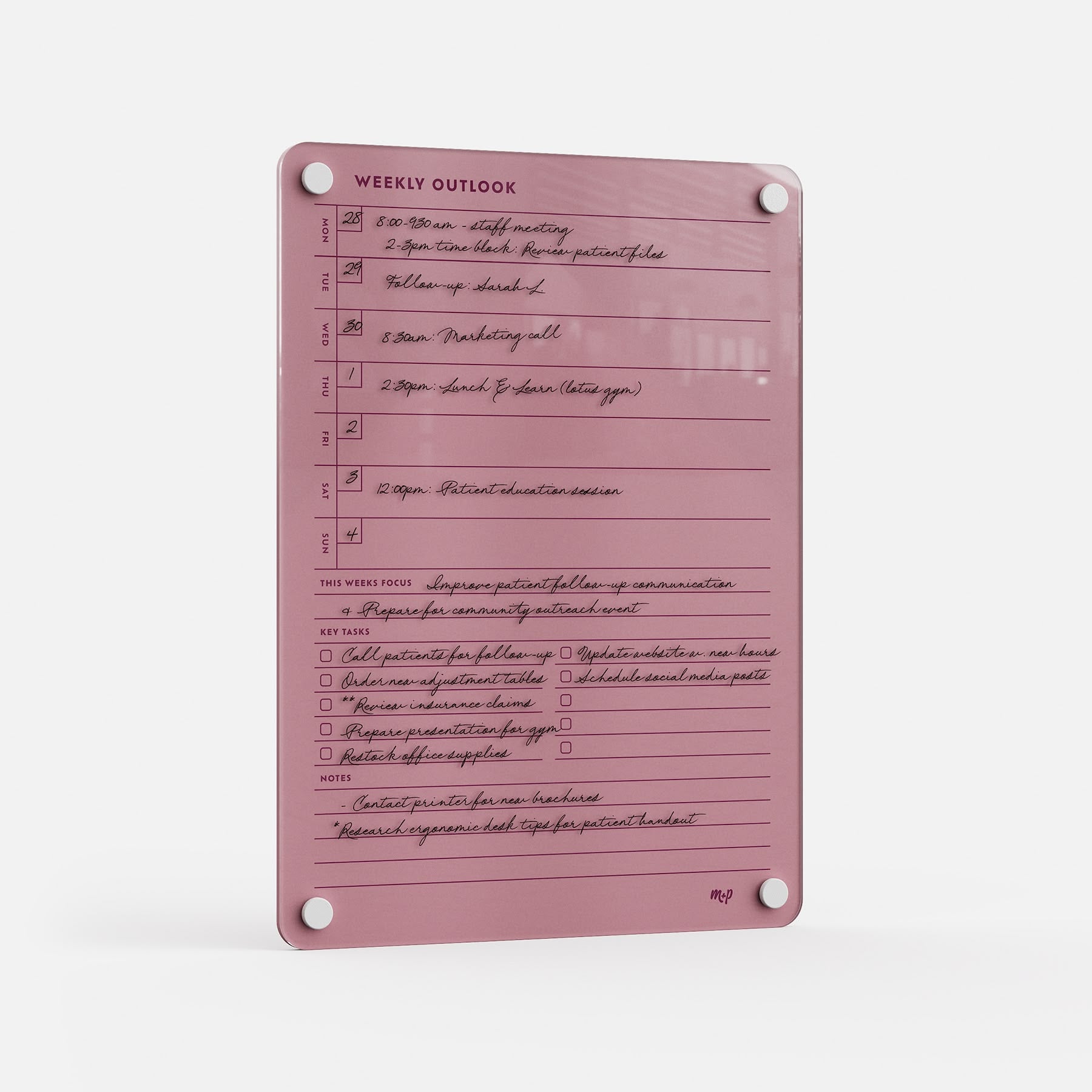 The Weekly Outlook 811 is a pink acrylic weekly planner board with handwritten schedules, black marker notes, sections for daily appointments, weekly focus, key tasks, and notes—a stylish organizer mounted via four corner holes.